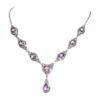 The Oval Amethyst with Pear Drop Necklace is a silver piece with symmetrically arranged oval and teardrop-shaped purple gemstones, featuring a dangling pendant.