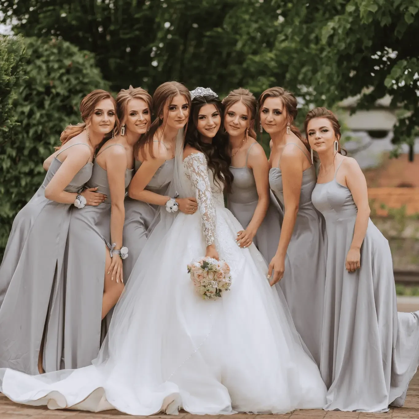 Bride with bridesmaids in gray dresses outside.