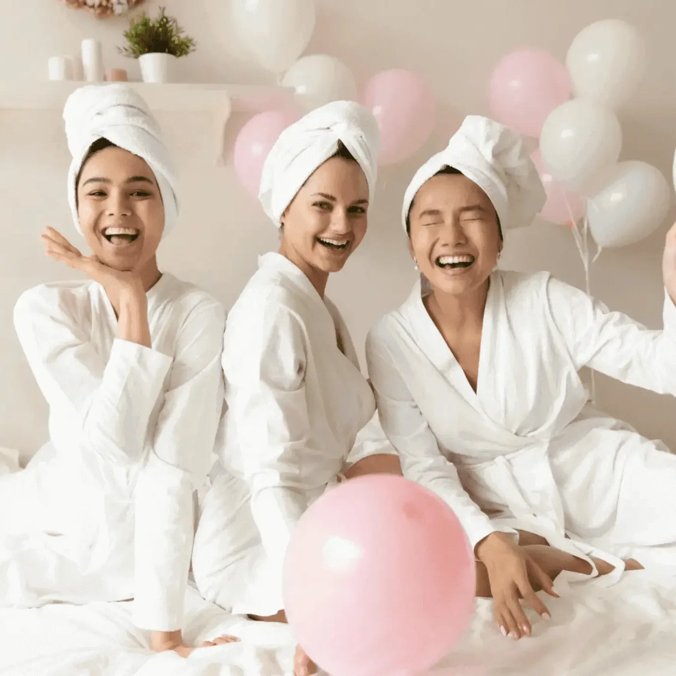 Three women with towel turbans and balloons and laughing